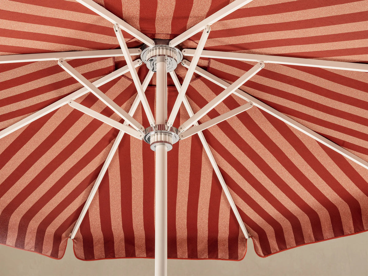 Top-down view of a red and light red/pink striped outdoor umbrella, featuring a chevron pattern radiating from the center.