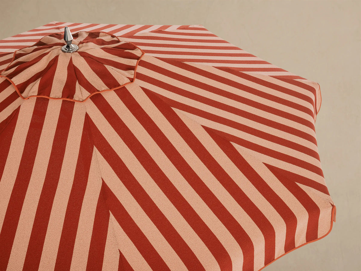 Interior view of a red and light beige striped umbrella, featuring white ribs, a white central pole, and silver mechanism.