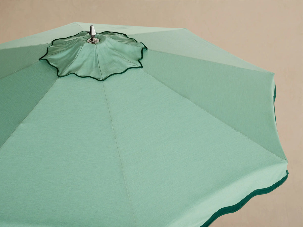 Interior view of a mint green umbrella showing the white support frame, central pole, and scalloped edge.