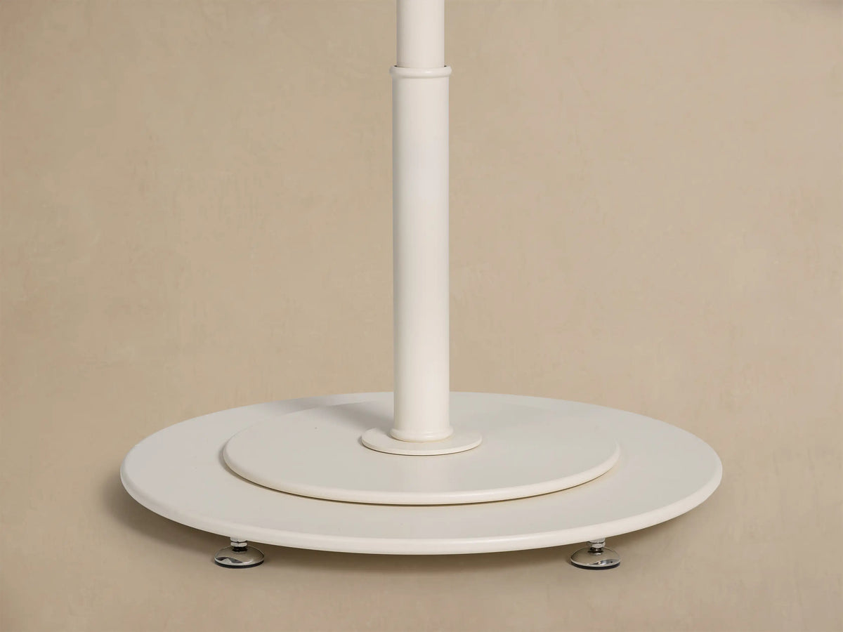 Close-up view of a cream umbrella canopy with a silver finial at the peak and cream fringe along the edge.