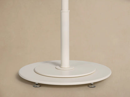 Close-up view of a cream umbrella canopy with a silver finial at the peak and cream fringe along the edge.