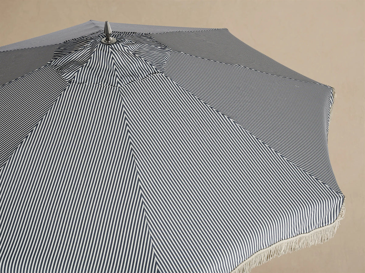 Interior view of a patio umbrella with a white and thin black striped canopy, white fringe, and cream frame.