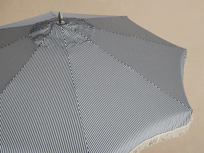 Interior view of a patio umbrella with a white and thin black striped canopy, white fringe, and cream frame.