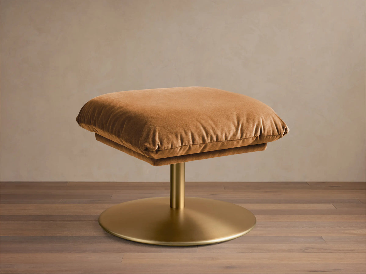 Front view of a Cognac velvet Deacon Ottoman with a gold finish pedestal base.