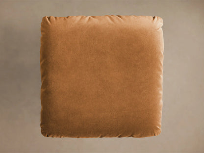 Front view of the caramel Deacon Ottoman, a plush square cushion on a shiny gold pedestal base.