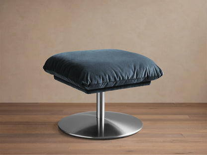 Front view of a dark teal Deacon Ottoman with a plush rectangular cushion and a silver circular pedestal base.