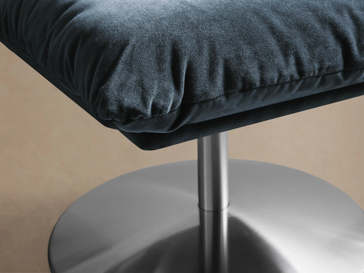 Front view of the dark blue plush Deacon Ottoman with a silver round pedestal base.