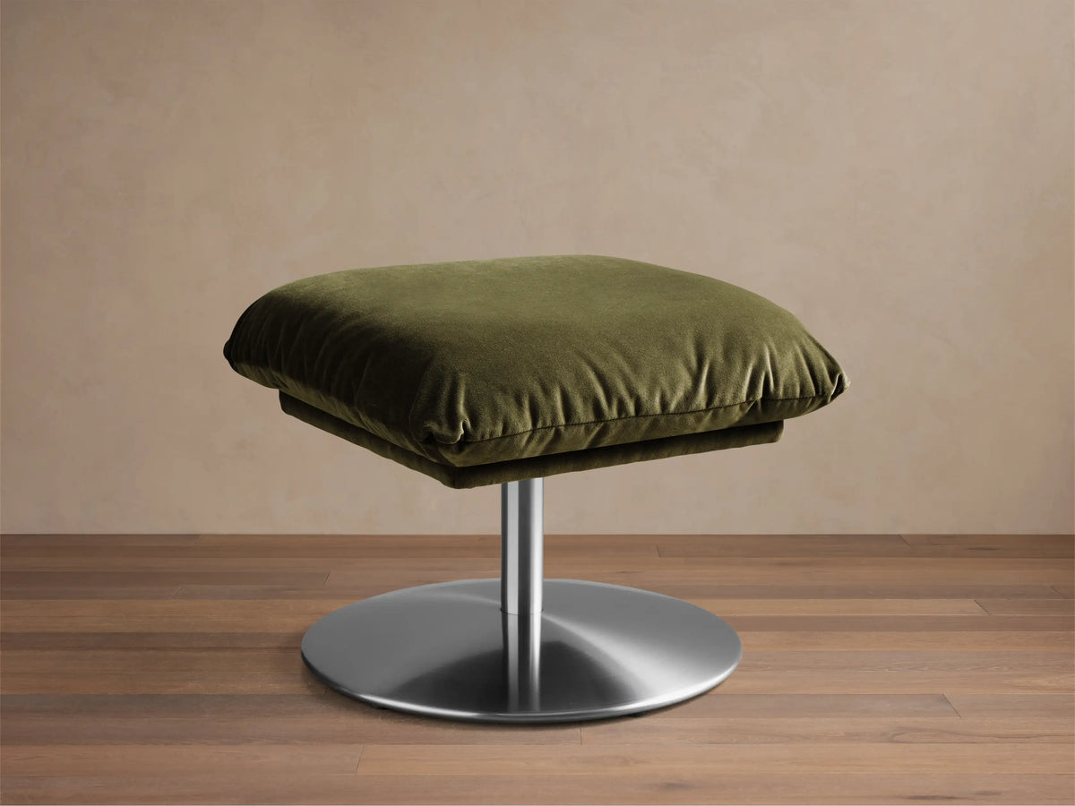 Front view of the Olive green Deacon Ottoman with a plush velvet cushion and round brushed silver metal base.