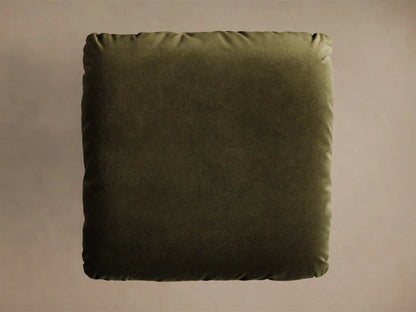 Close-up of the olive green velvet cushion and round brushed metal base of the Deacon Ottoman.