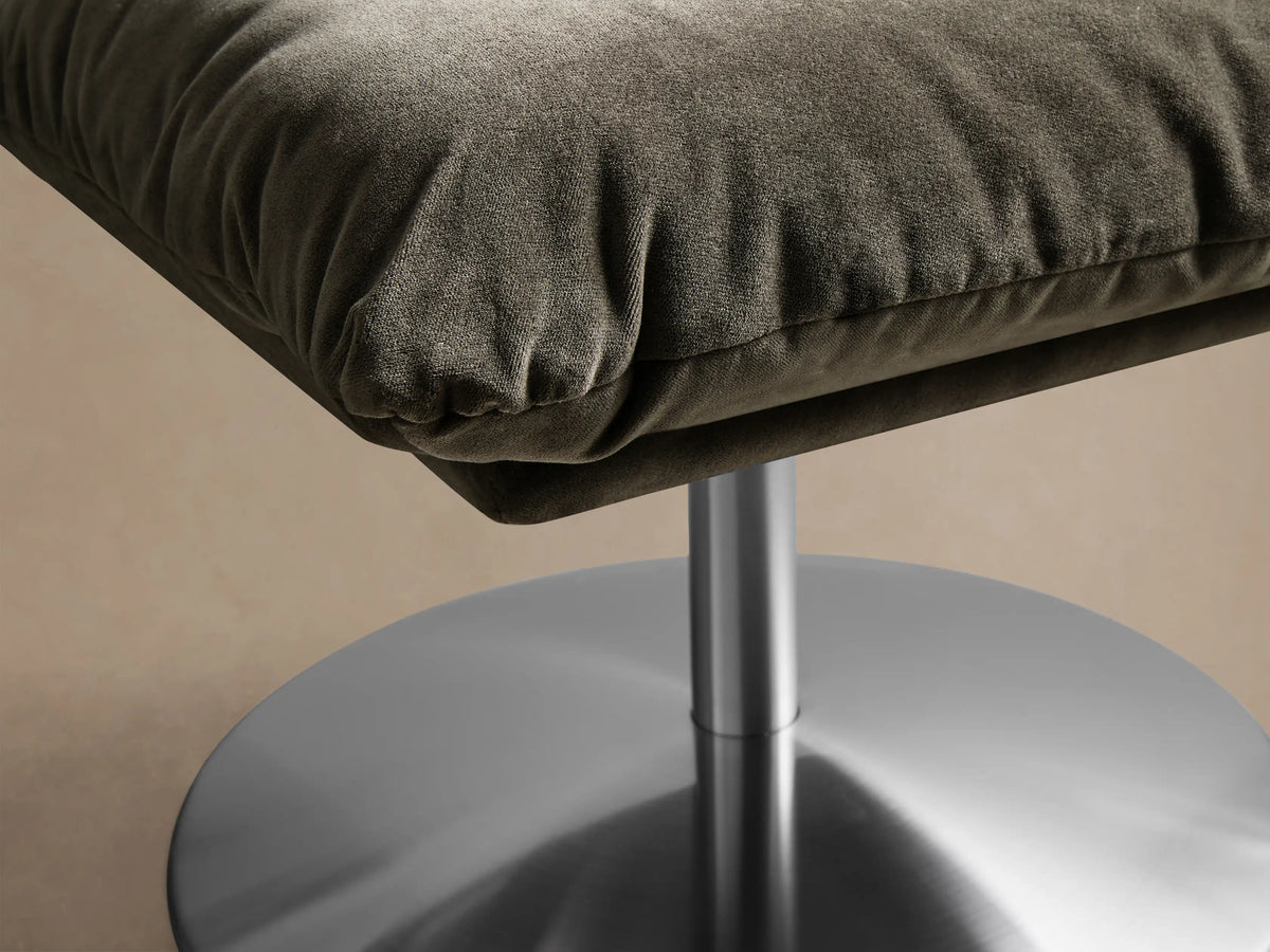 Front view of the olive green velvet Deacon Ottoman, featuring a plush cushion and a brushed silver pedestal base.