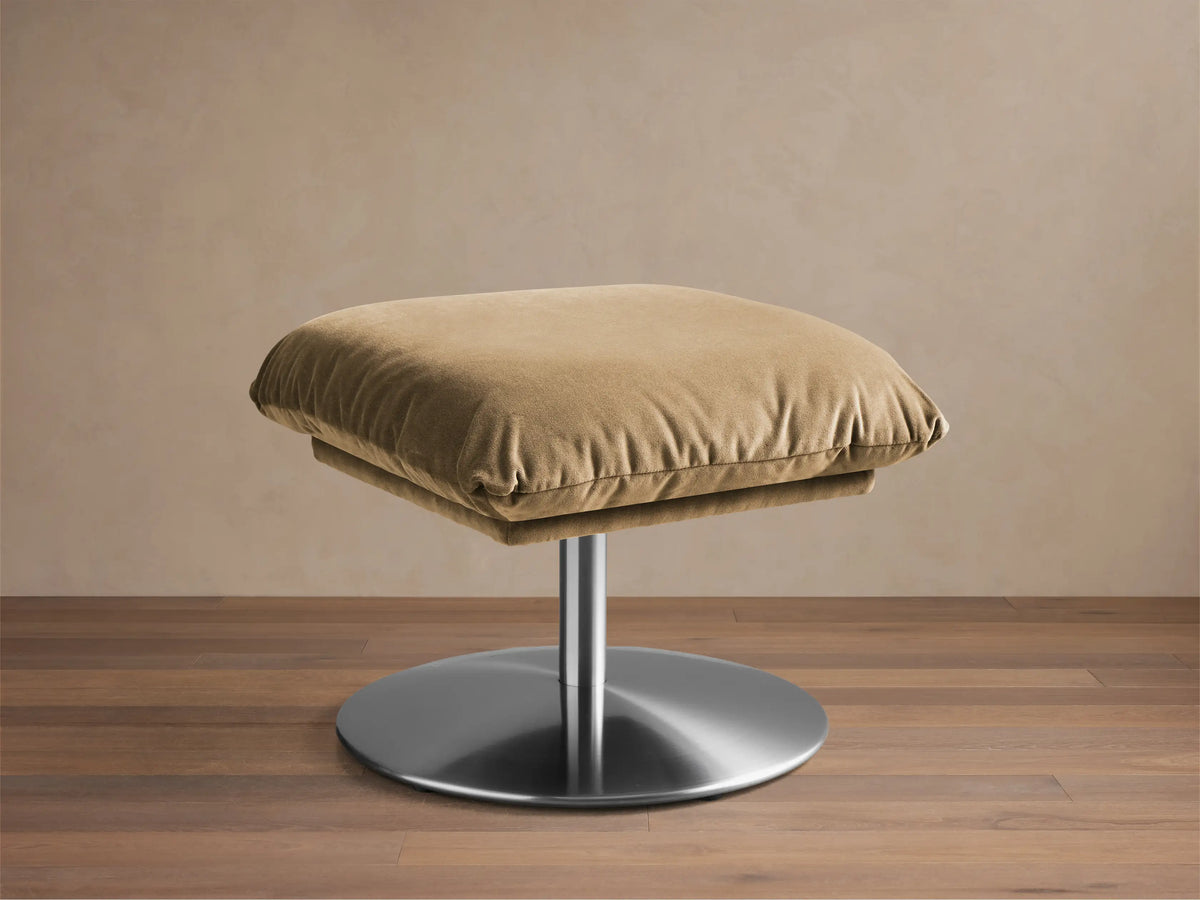 Front view of the tan velvet Deacon Ottoman with a brushed metal swivel base.