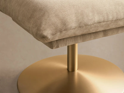 Front view of the beige Deacon Ottoman with a square cushion and a round gold metal base.