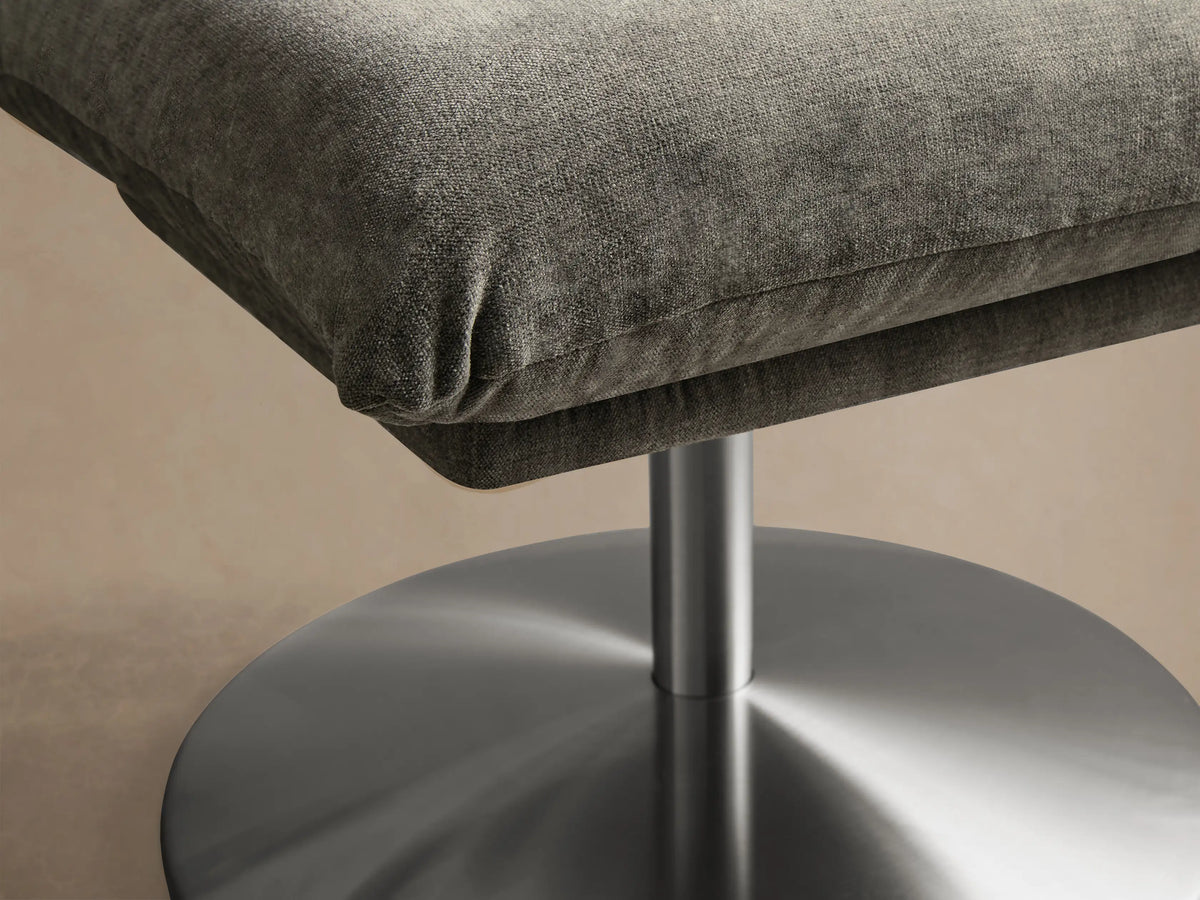 Front view of the light gray Deacon Ottoman, featuring a square cushion and a round brushed silver base.