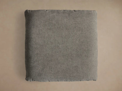 Close-up of the charcoal Deacon Ottoman with a textured cushion resting on a round, brushed silver steel base.