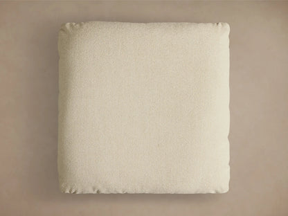 Close-up of the beige textured cushion, silver cylindrical support, and round brushed metal base of the Deacon Ottoman.