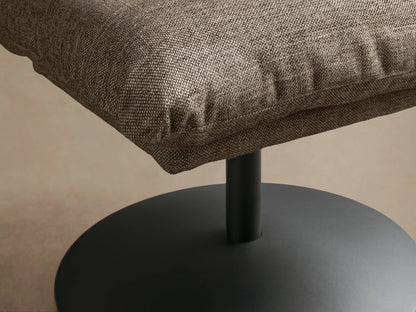 Front view of the brown-grey heathered Deacon Ottoman, featuring a plush cushion and black metal pedestal base.