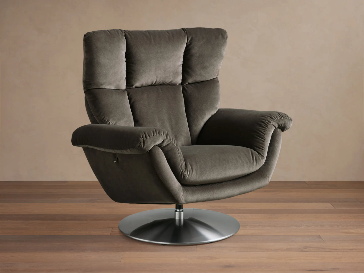 Side view of the dark gray Deacon Swivel Recliner with a channeled backrest and silver swivel base, in a reclined position.