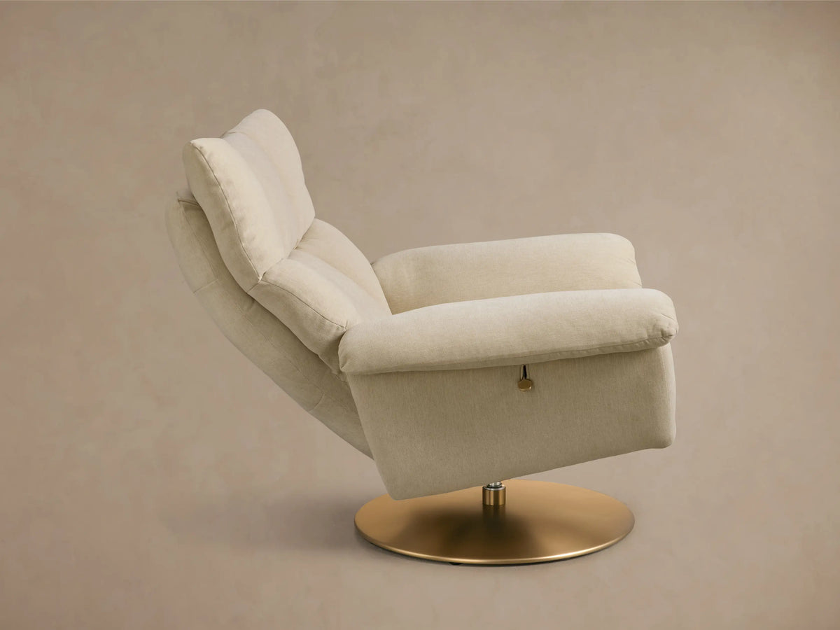 Rear-side view of a plush beige Deacon Swivel Recliner with a gold-toned round swivel base.
