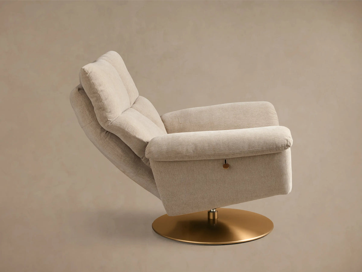 Rear-side view of the beige Deacon Swivel Recliner, showing plush back cushioning and a round gold swivel base.