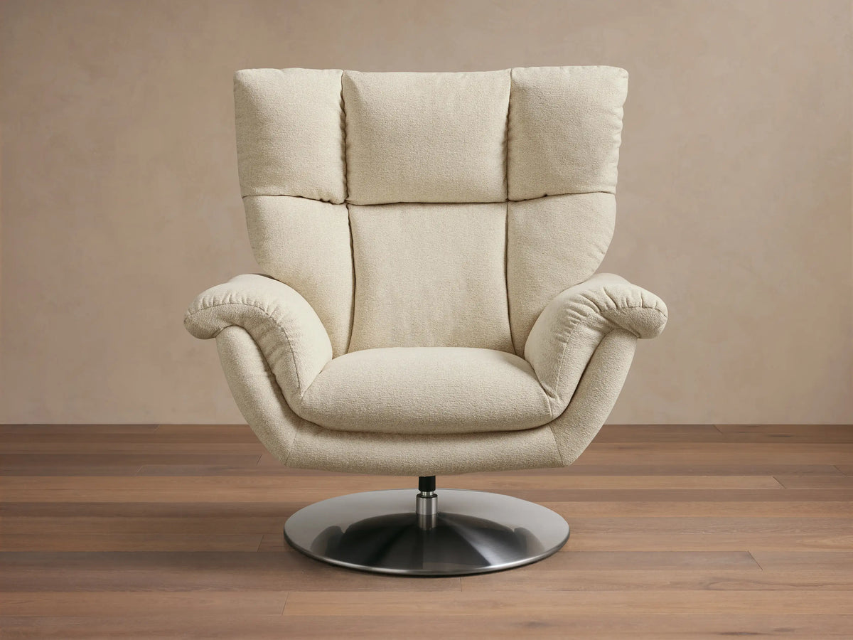 Front view of the creamy beige Deacon Swivel Recliner, showing its textured fabric, padded back, armrests, and silver swivel base.