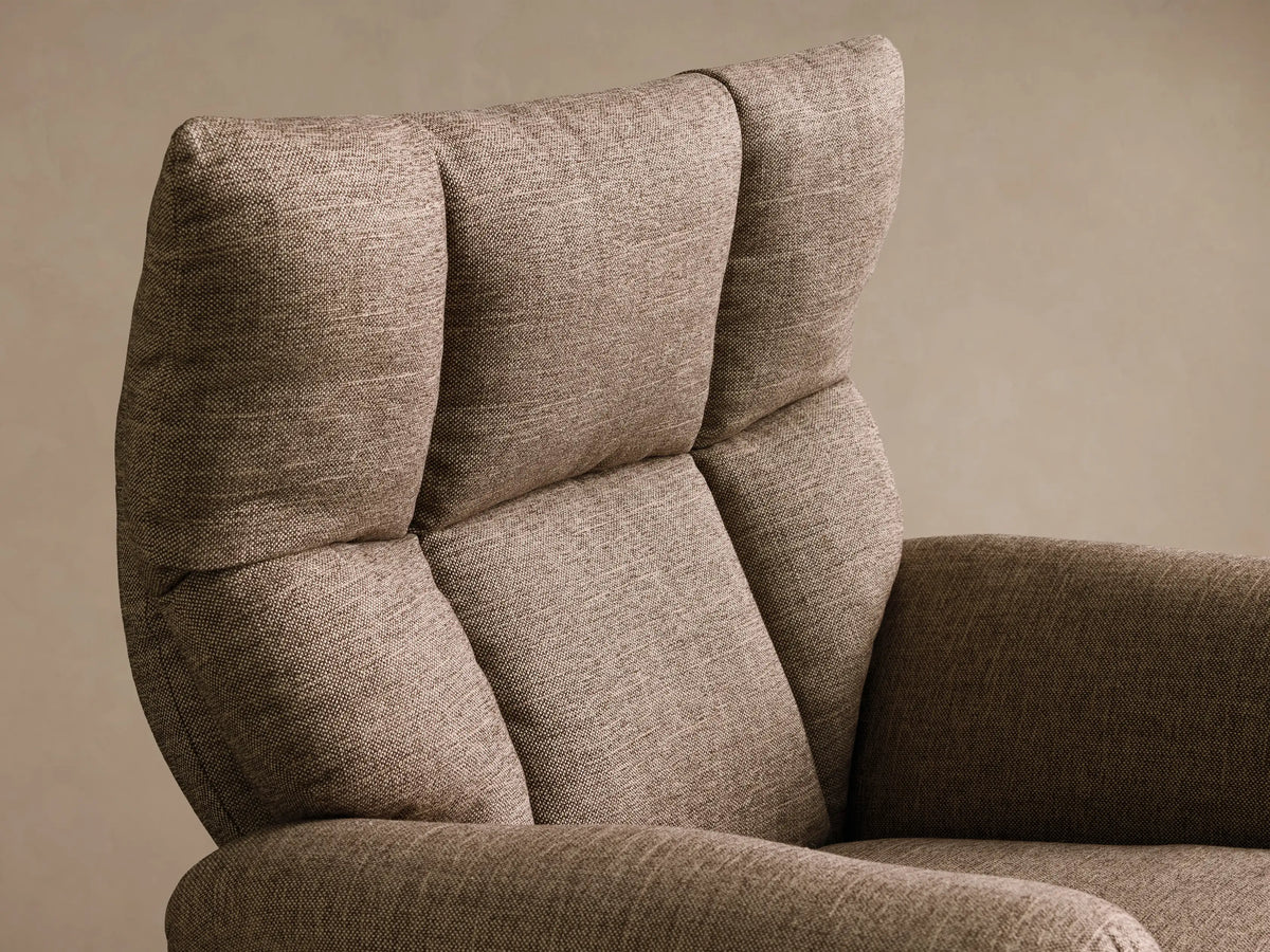 Close-up of the brown woven fabric on the multi-paneled backrest and curved armrest of the Deacon Swivel Recliner.