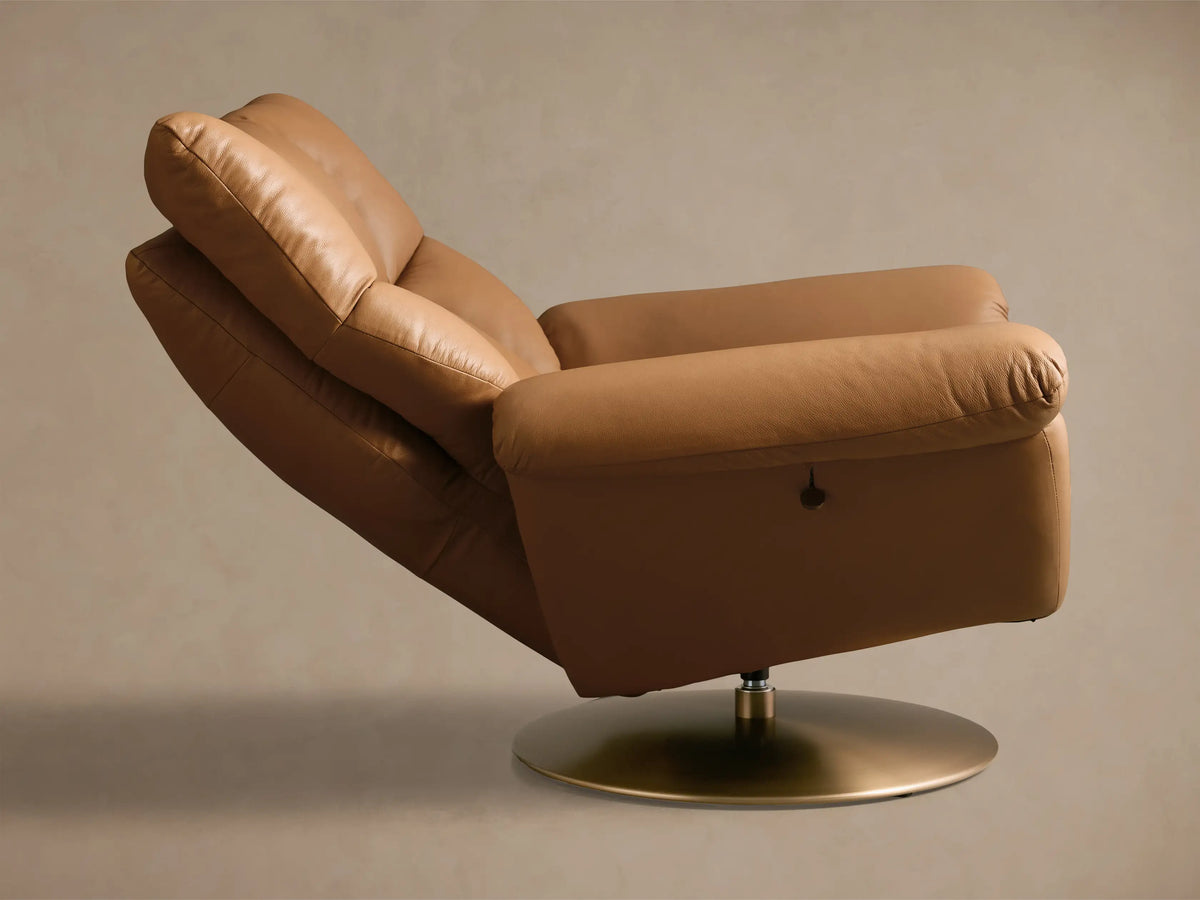 Front-left view of a Tan Deacon Leather Swivel Recliner, featuring soft, tufted cushions and a gold swivel base.