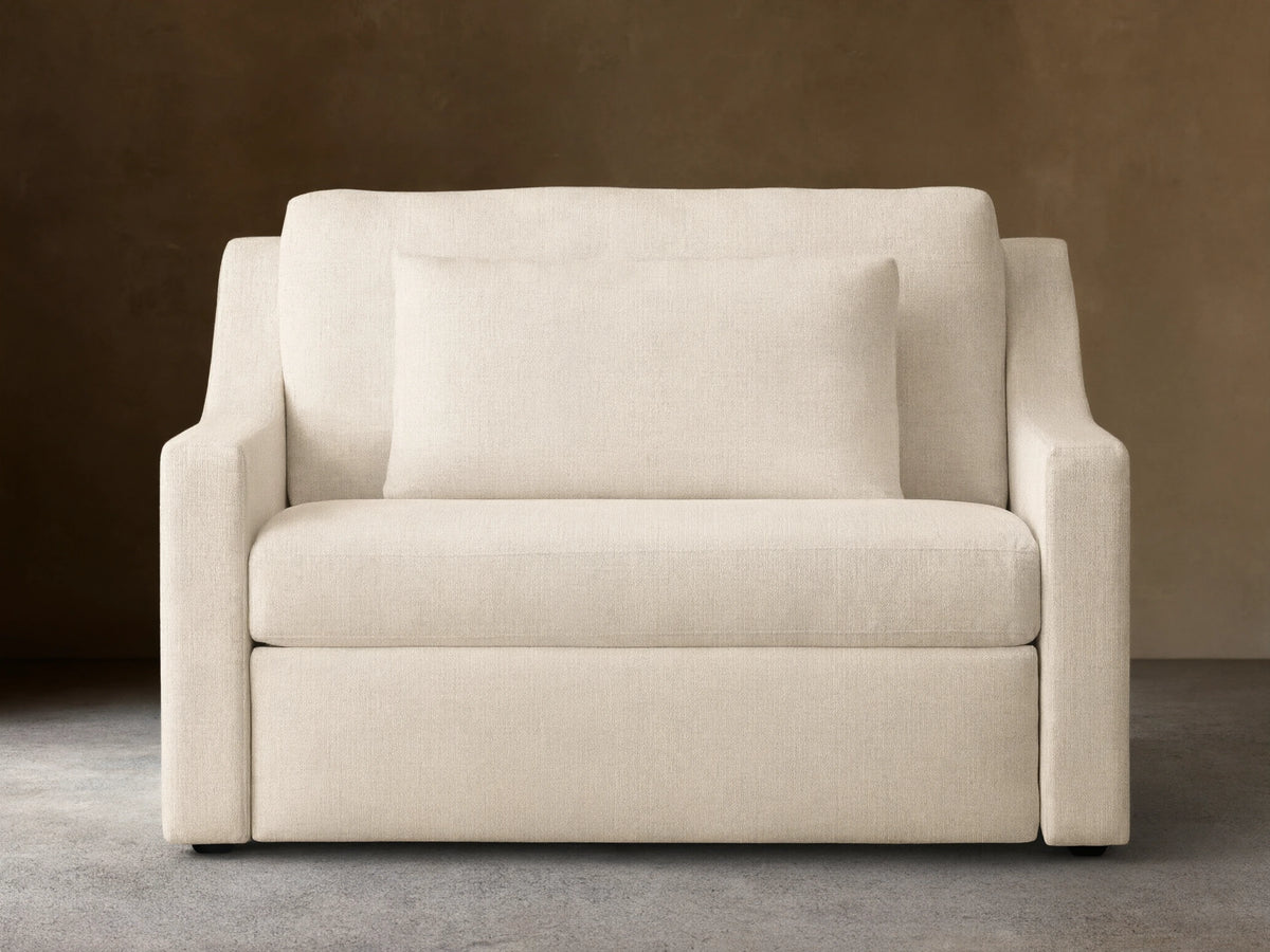 Front view of Ashby Luxury Twin Sleeper Chair in beige fabric, featuring plush seat and back cushions, with wooden floor and neutral wall background.