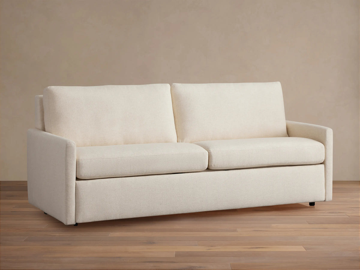 Kipton Slim Arm Luxury King Sleeper Sofa in Wiley Parchment, a light beige fabric, with slim arms, two seat and back cushions.