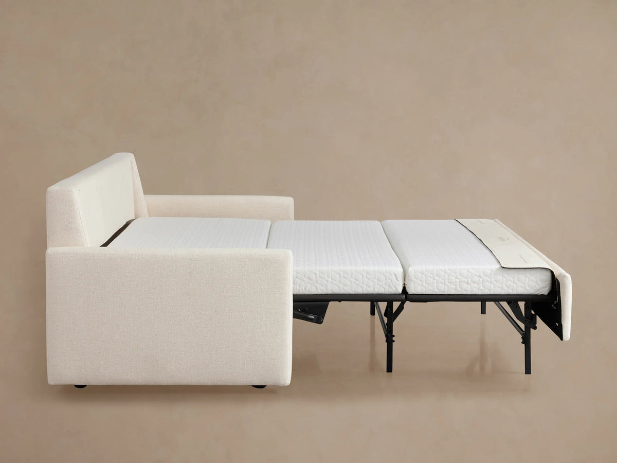 Kipton King Sleeper Sofa, Wiley Parchment. Partially open, white quilted mattress extends from black pull-out frame.
