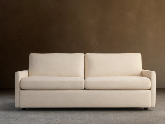 Kipton Slim Arm Luxury King Sleeper Sofa in Wiley Parchment, a light beige fabric, with slim arms, two seat and back cushions.