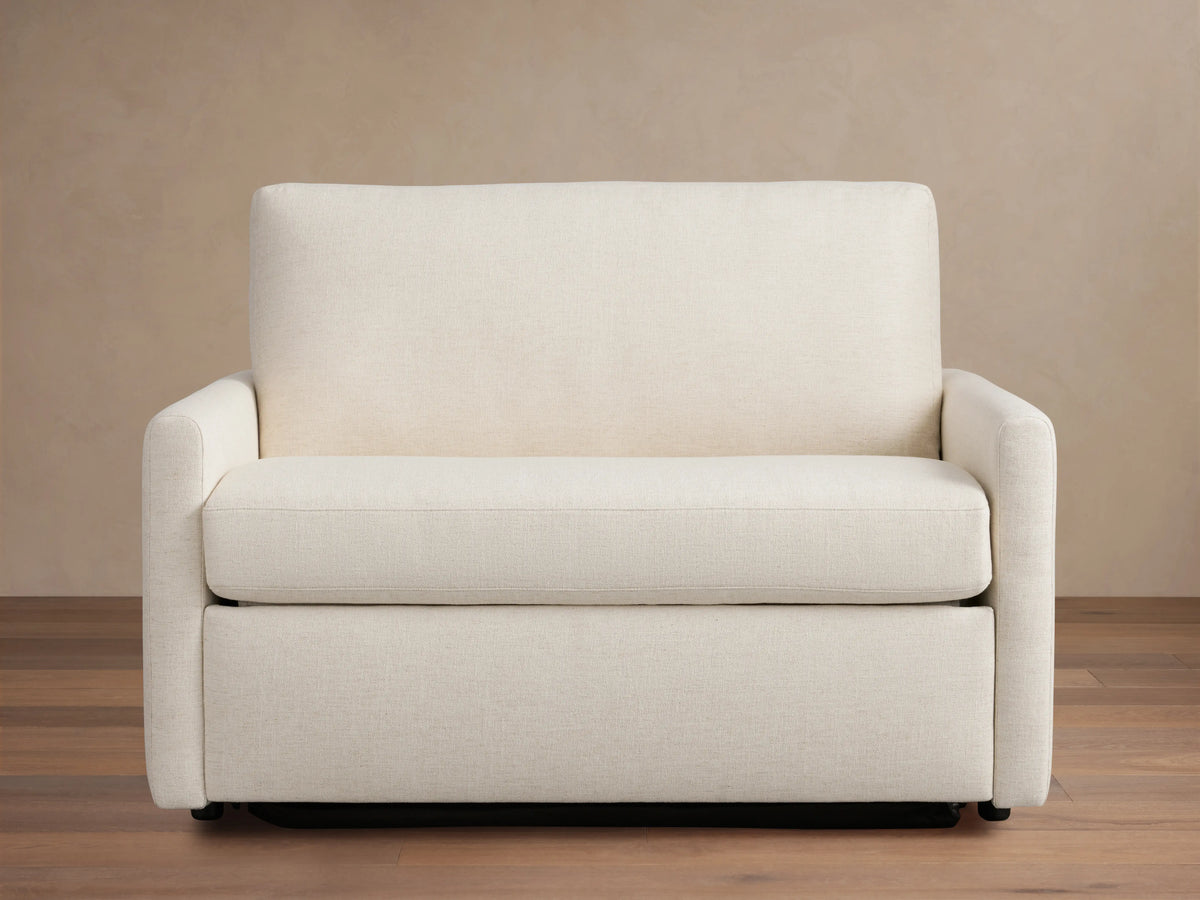 Kipton Slim Arm Luxury Twin Sleeper Chair in beige fabric, straight view. Features slim arms, plush seat, and back cushion on wooden floor.