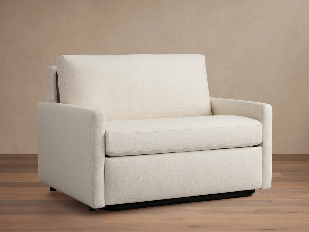Kipton Slim Arm Luxury Twin Sleeper Chair in beige fabric, straight view. Features slim arms, plush seat, and back cushion on wooden floor.