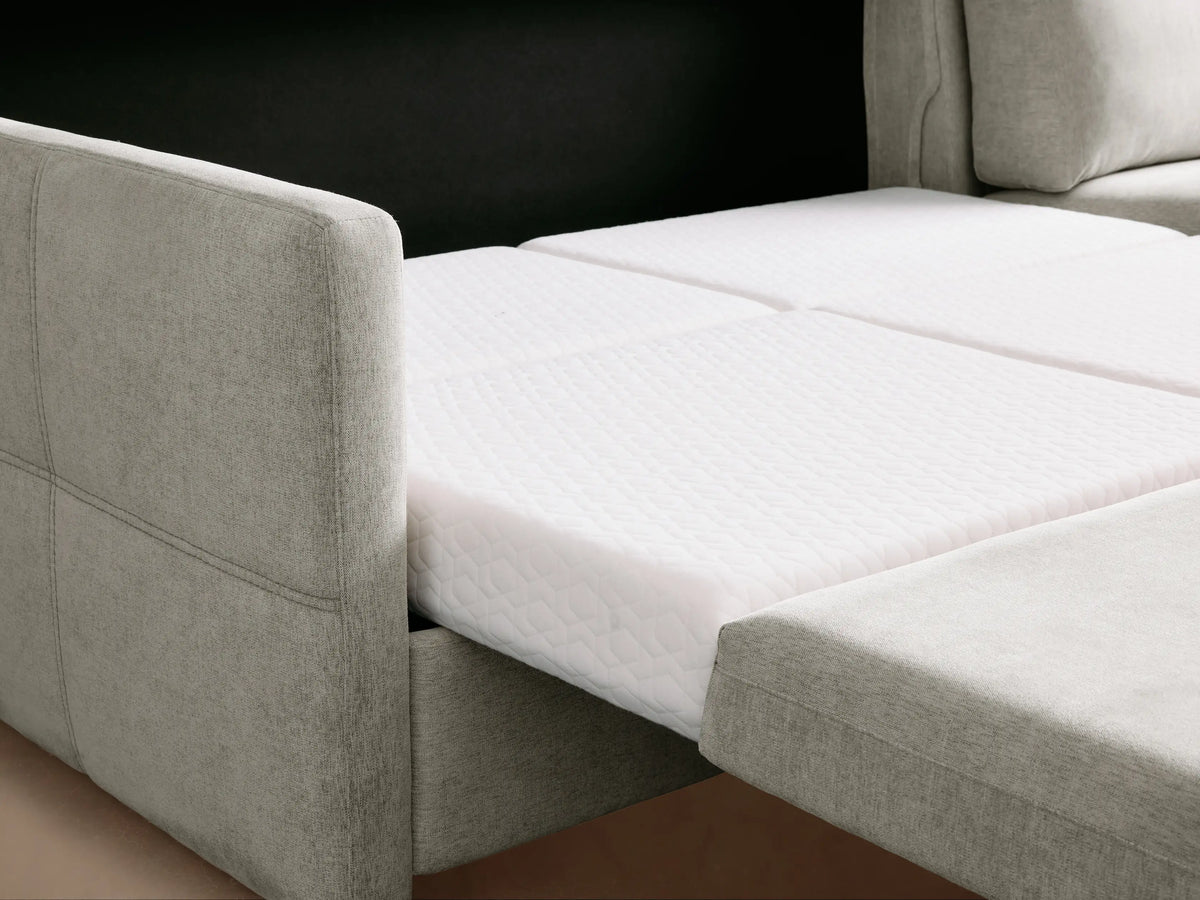 Reece Two-Piece Sleeper Chaise Sectional in light grey fabric, L-shaped with a right-facing chaise, on a wooden floor.