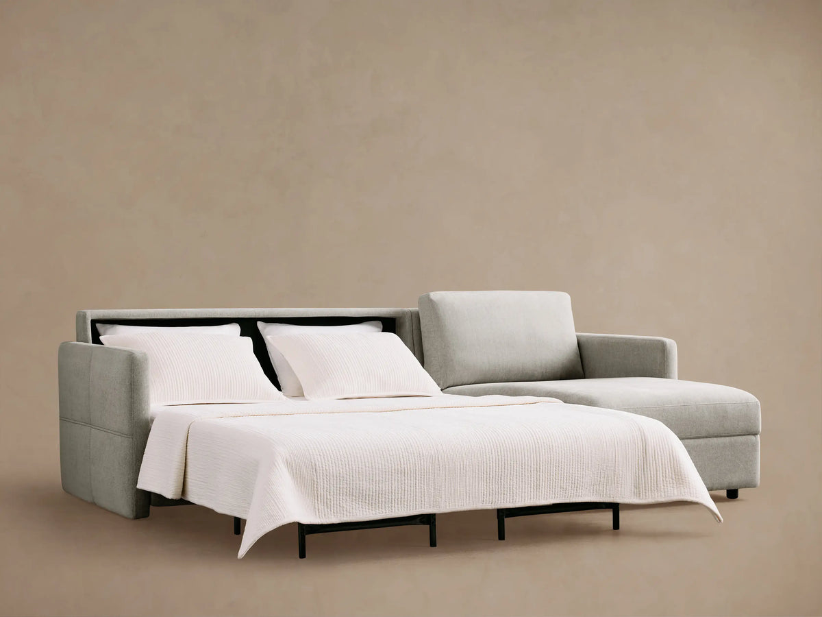 Reece Two-Piece Sleeper Chaise Sectional, light gray, partially opened with white mattress extended & black supports. Chaise on right.