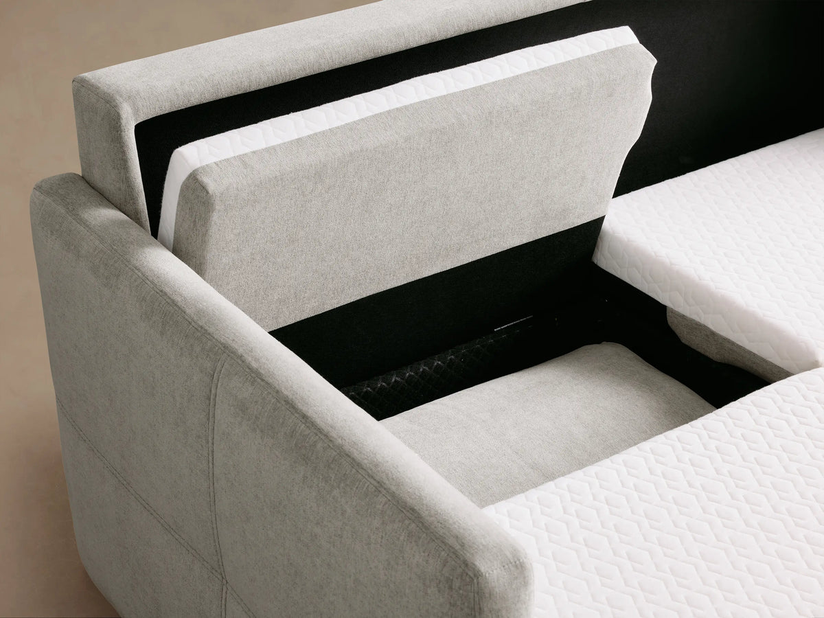 Close-up of gray Reece Sleeper Chaise Sectional with backrest lifted, exposing the white mattress & black interior.