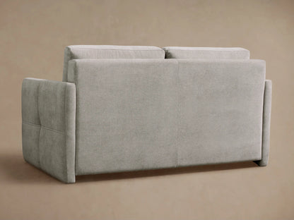 Close-up of Reece Sleeper Sofa in light gray fabric, with its backrest cushion lifted to reveal a white quilted mattress and black interior.