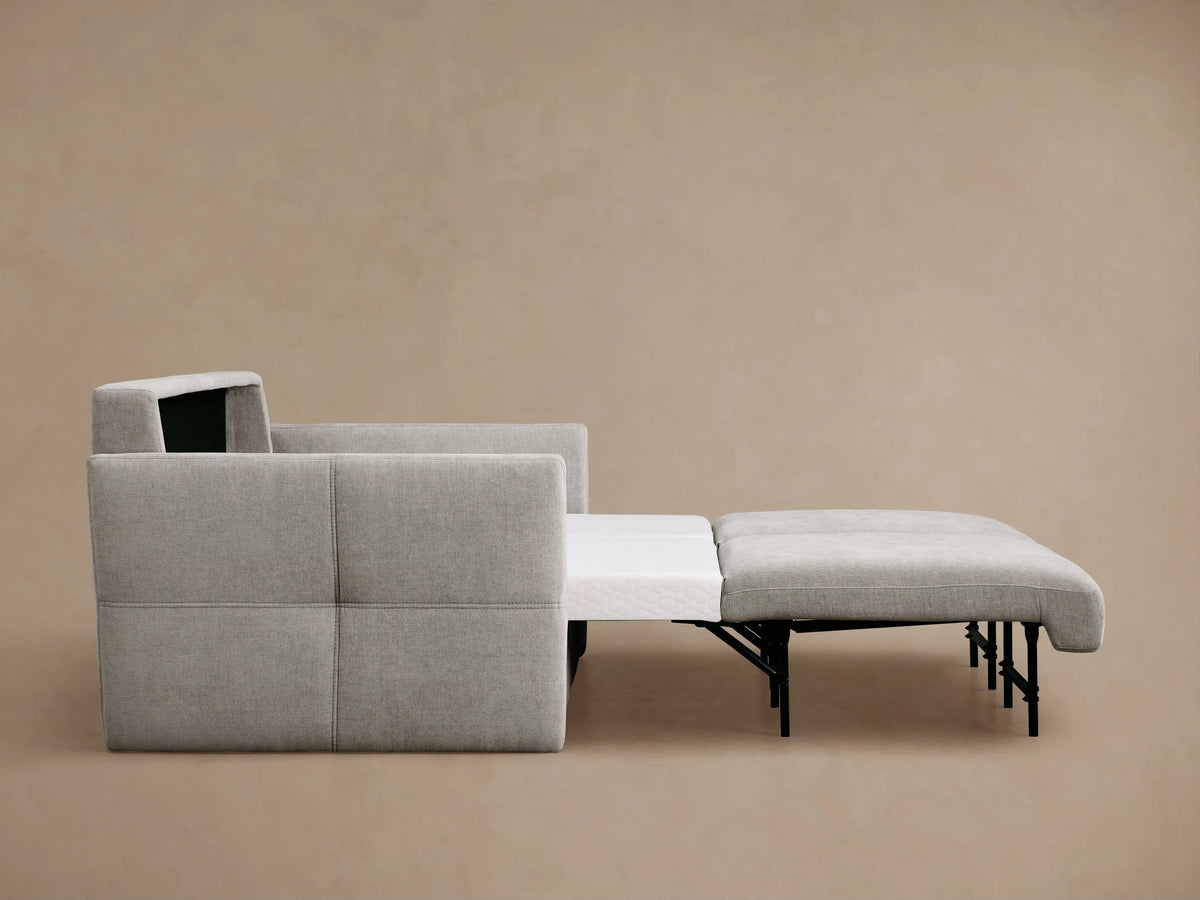 Back and side view of a light gray Reece Sleeper Sofa with textured fabric, two visible back cushions, and a subtly tufted left arm.