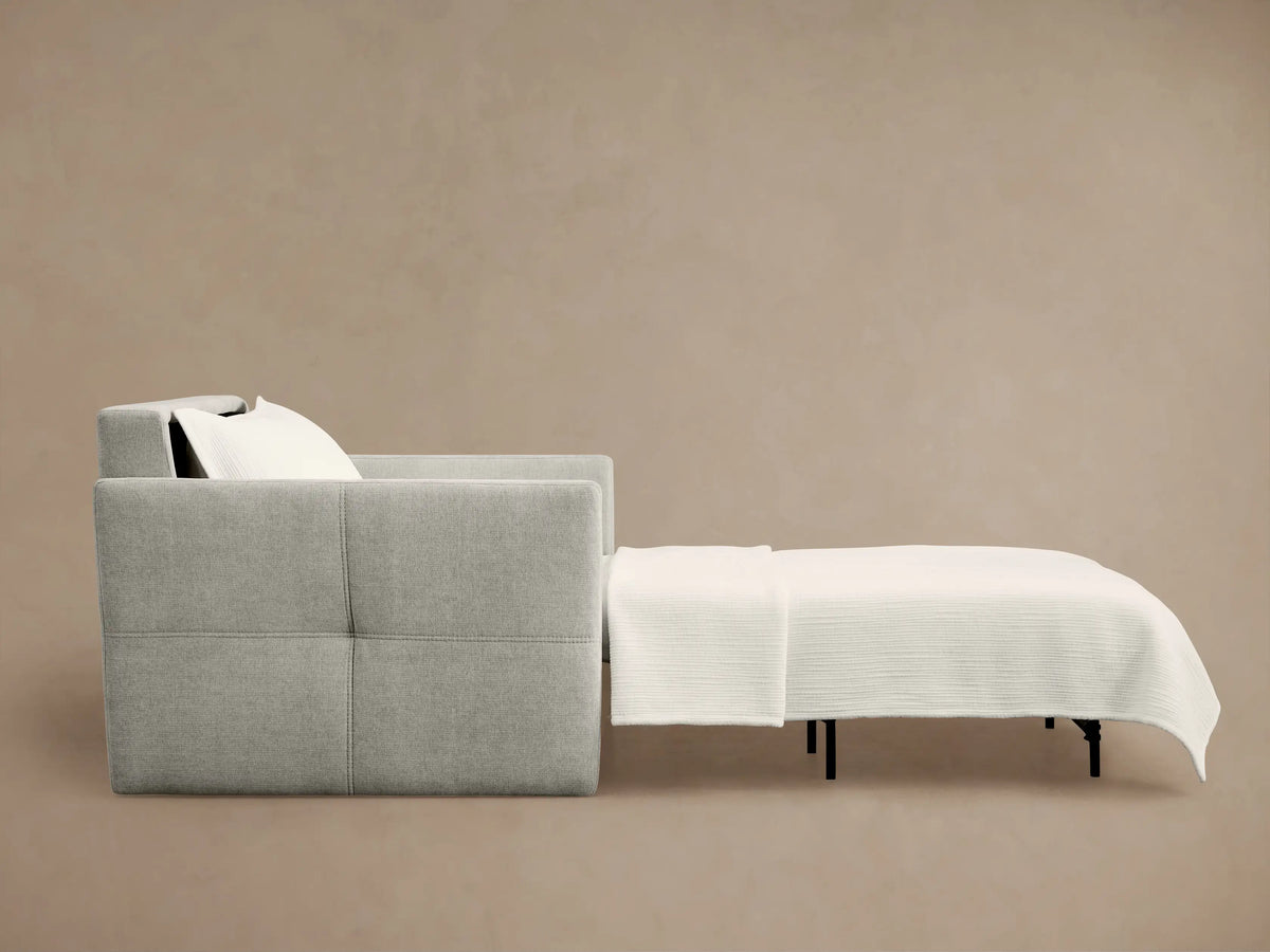Side view of light gray Reece Twin Sleeper Chair, partially extended as a bed with white mattress and black support legs.