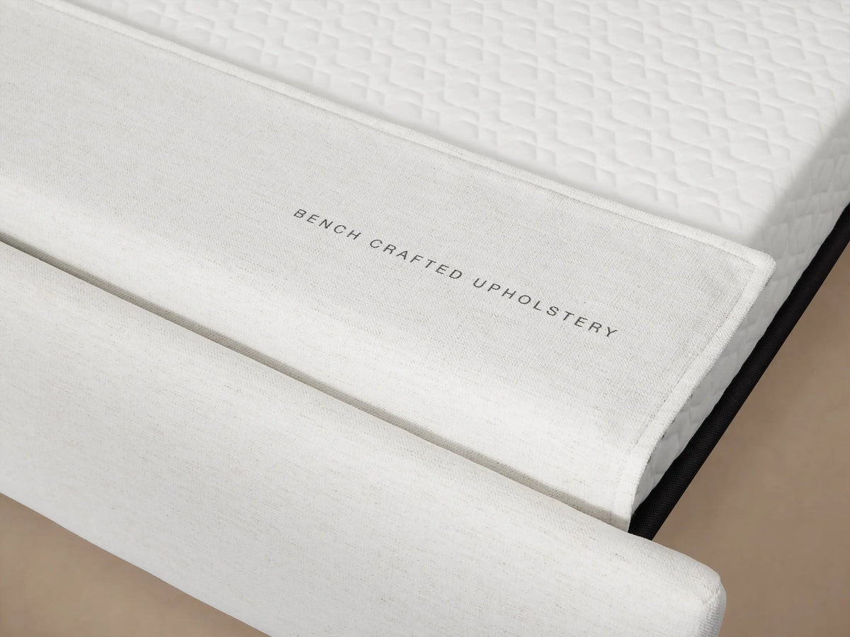 Close-up of Remington Luxury Sleeper Sofa's off-white, textured fabric on the back cushion and armrest, against a muted tan wall.