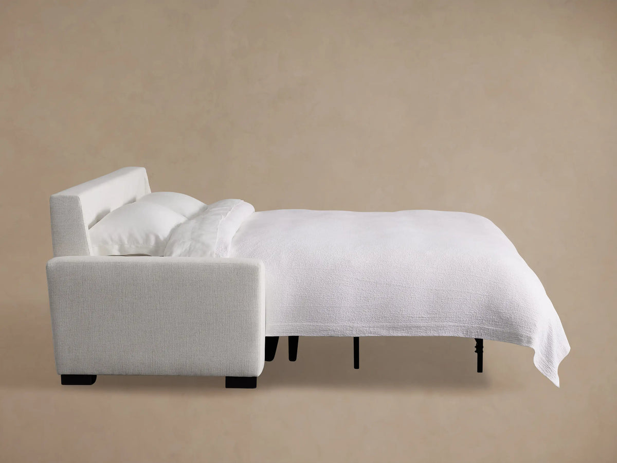 Back and left side view of a white Remington Luxury Sleeper Sofa with textured fabric and dark feet on a beige background.