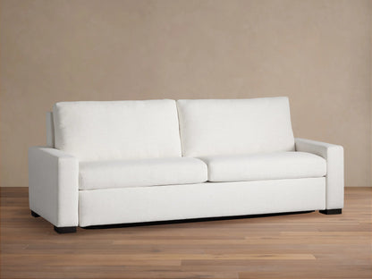 White textured Remington Luxury Sleeper Sofa with two cushions, wide arms, on a wood floor against a beige wall.
