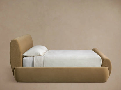 Rounded edge of the Wynn Bed headboard upholstered in a light tan fabric, showing a vertical seam.