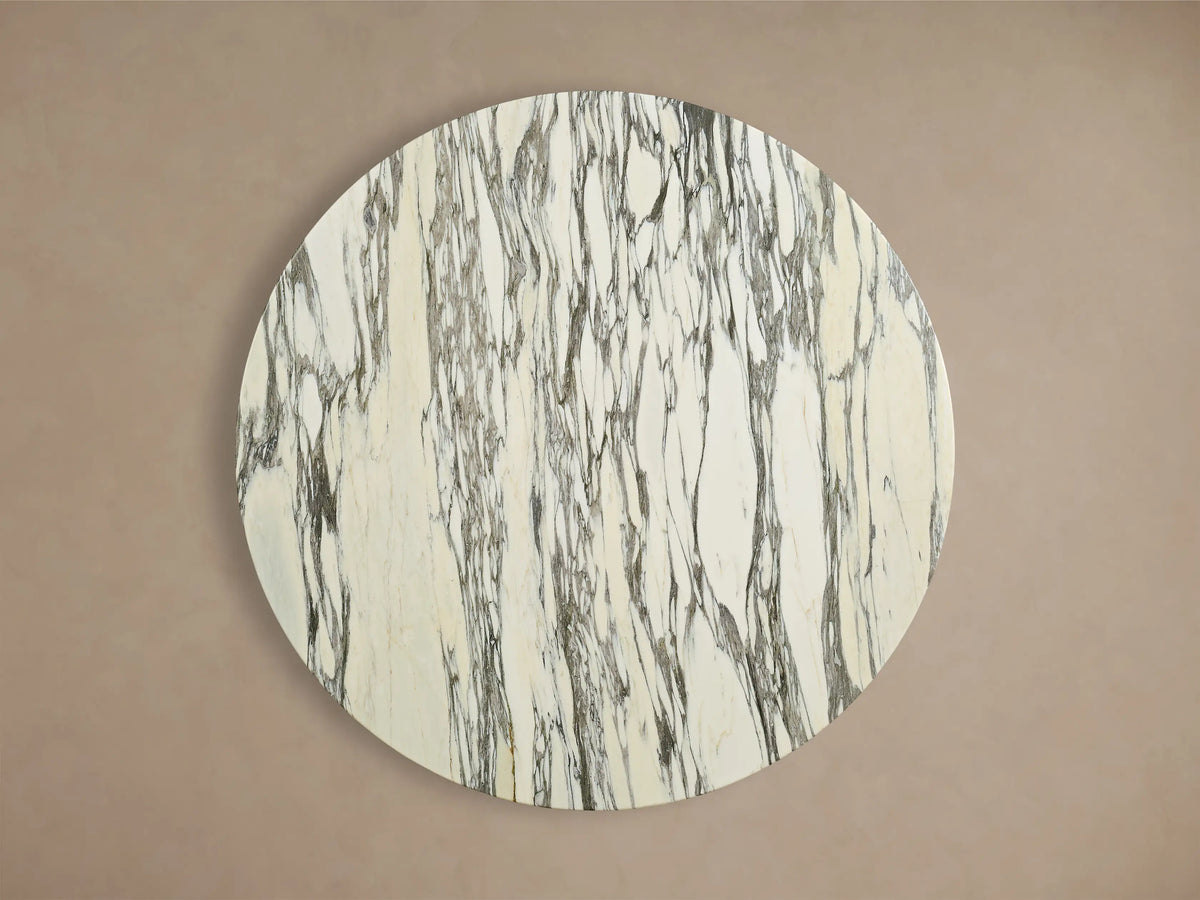 Front view of the Saint Germain Round Stone Dining Table with Toulouse Base, featuring a white honed stone top with gray veining and a black tapered base.