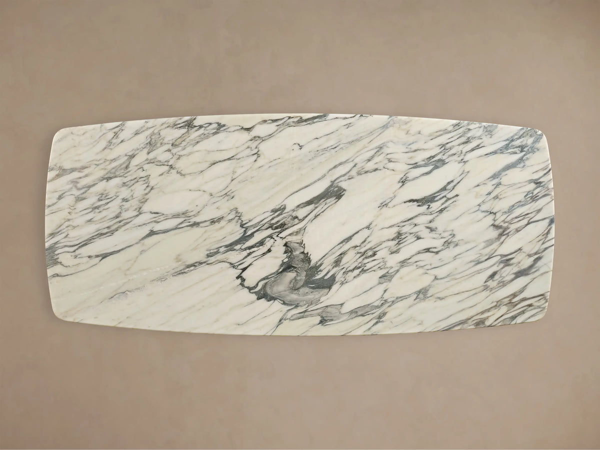 Front view of the Saint Germain Stone Dining Table with Toulouse Base, featuring a white honed stone top with gray veining and a black engineered hardwood base.
