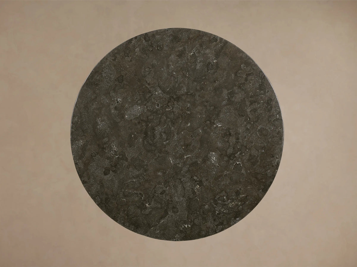Close-up of the dark gray honed stone tabletop with natural variations on the Saint Germain Round Stone Dining Table with Toulouse Base.
