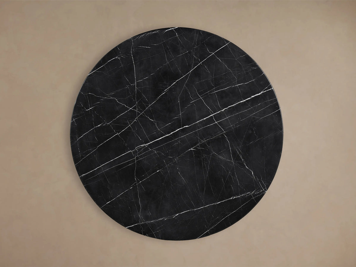 Front view of the Saint Germain Round Stone Dining Table with a black marbled stone top and curved oak veneer Dauphine base.
