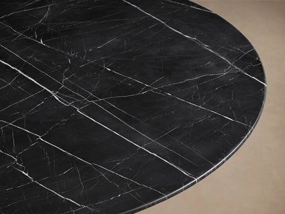 Front view of the black Saint Germain Round Stone Dining Table with Toulouse Base, featuring a dark stone top with white veining and a tapered black wood base.