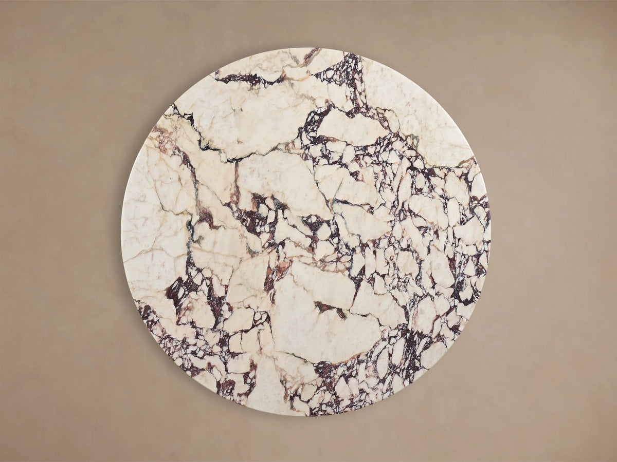 Front view of Saint Germain Round Stone Dining Table with Toulouse Base, white stone top with dark veining, black wood grain base.