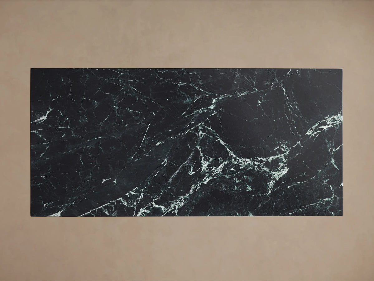 Front view of a dark green marble dining table with prominent white veining, featuring a thick rectangular top and a solid tapered trapezoidal pedestal base.