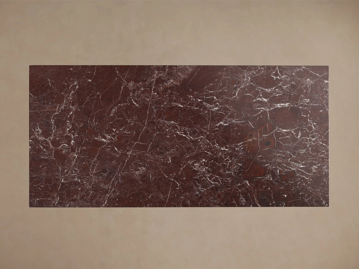 Front view of a dark red marble table with a rectangular top and a trapezoidal base, featuring white veining.